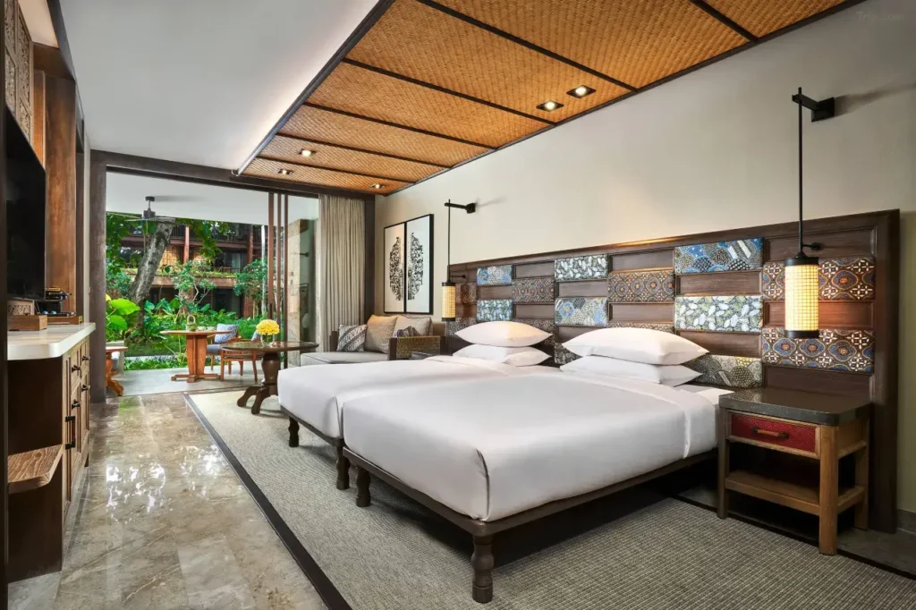 Andaz Bali's elegant swimming pool area is surrounded by lush gardens, reflecting its village-concept design. This modern resort is known for its flexible late check-out availability.