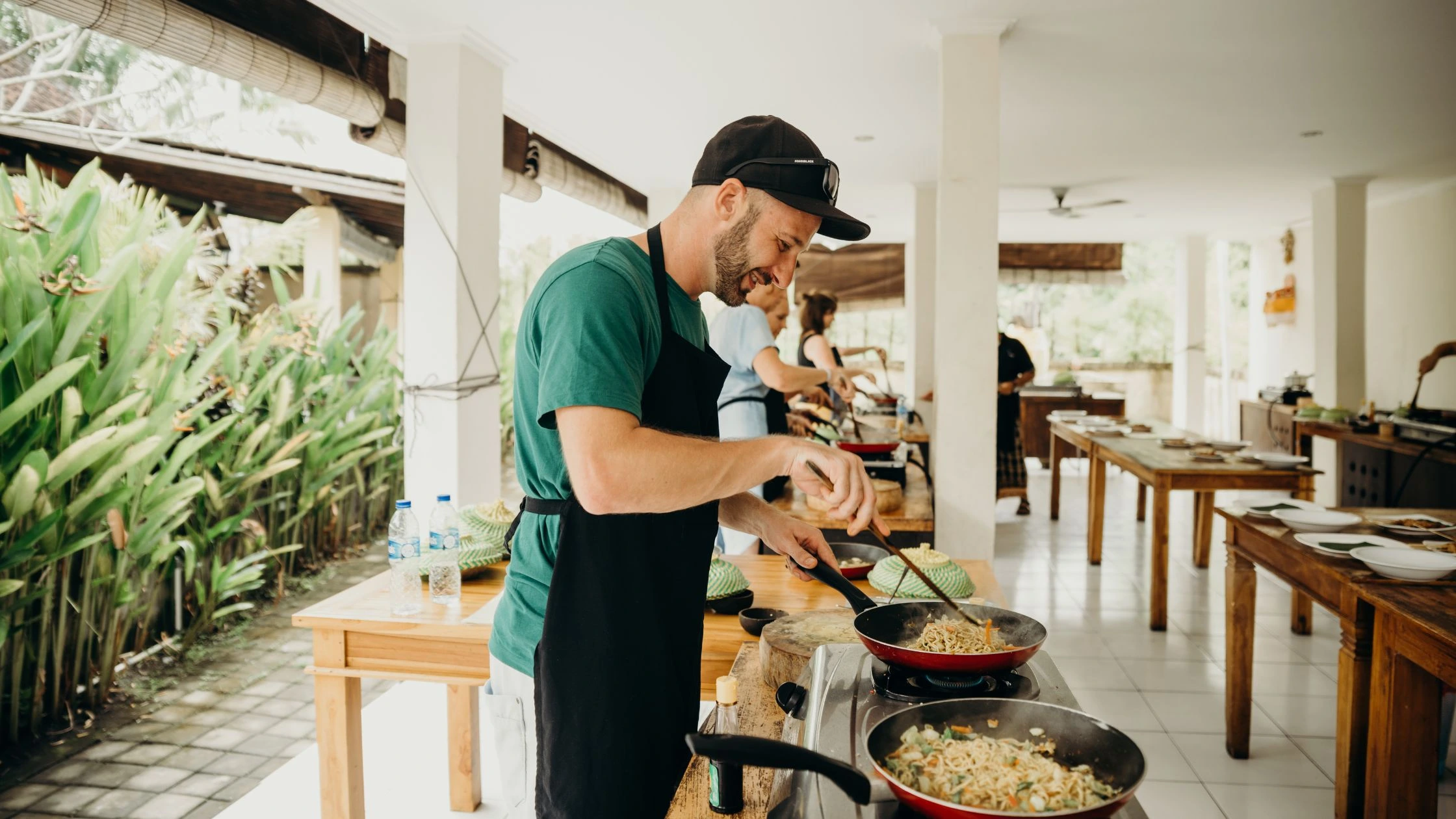 Students enthusiastically learn to cook local dishes from an expert chef in Bali.