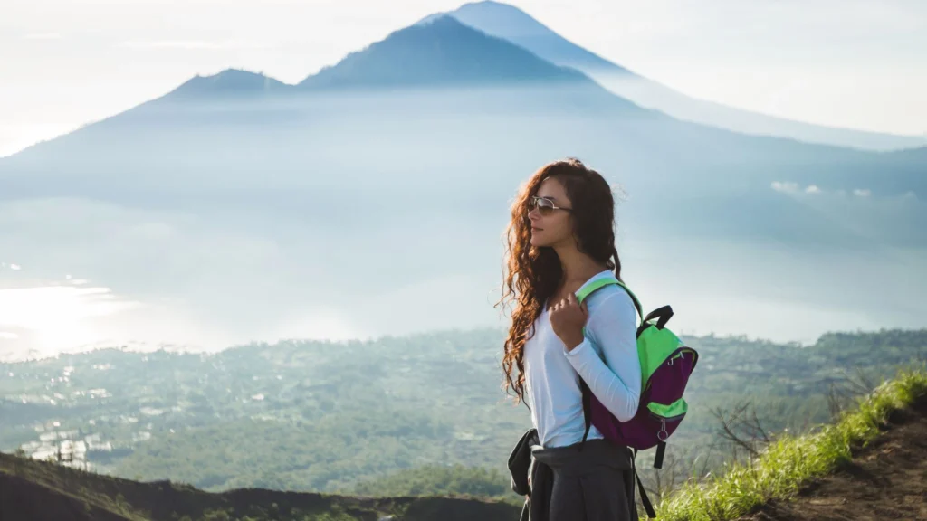 The golden hues of a sunrise illuminate the path as trekkers make their way up a Balinese mountain. This scene captures the serene beauty and physical exertion of a sunrise trekking adventure in Bali.