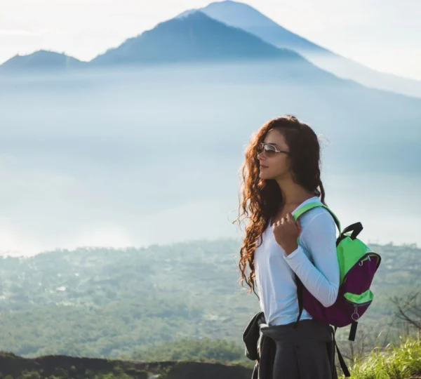 The golden hues of a sunrise illuminate the path as trekkers make their way up a Balinese mountain. This scene captures the serene beauty and physical exertion of a sunrise trekking adventure in Bali.