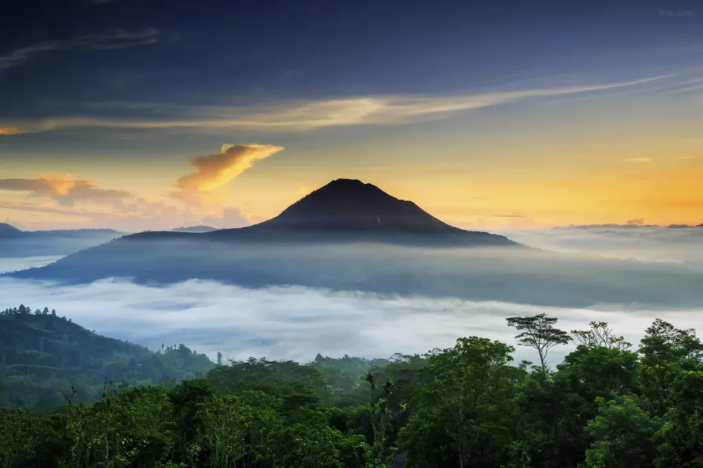 An aerial view shows a group of tourists embarking on a Mount Batur tour in Bali. The image captures the beginning of their journey, highlighting the popular volcanic landscape.