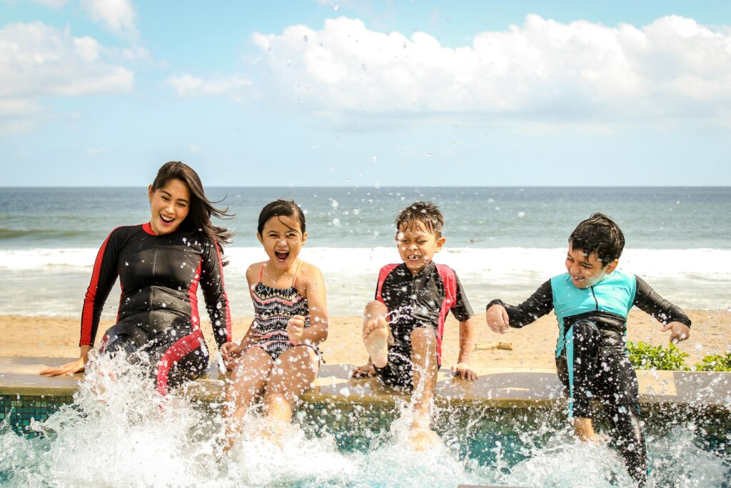 A family having fun splashing water near the seashore on a sunny day in Bali, Indonesia, bali hotels family and kids friendly.