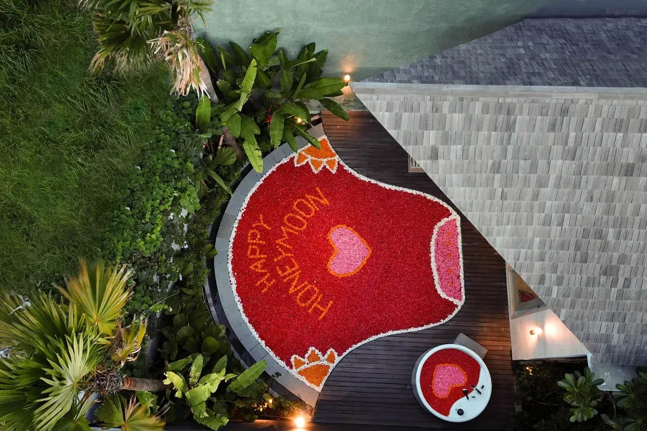 Red flowers floating in a private pool, set up to welcome a couple on their Bali honeymoon.