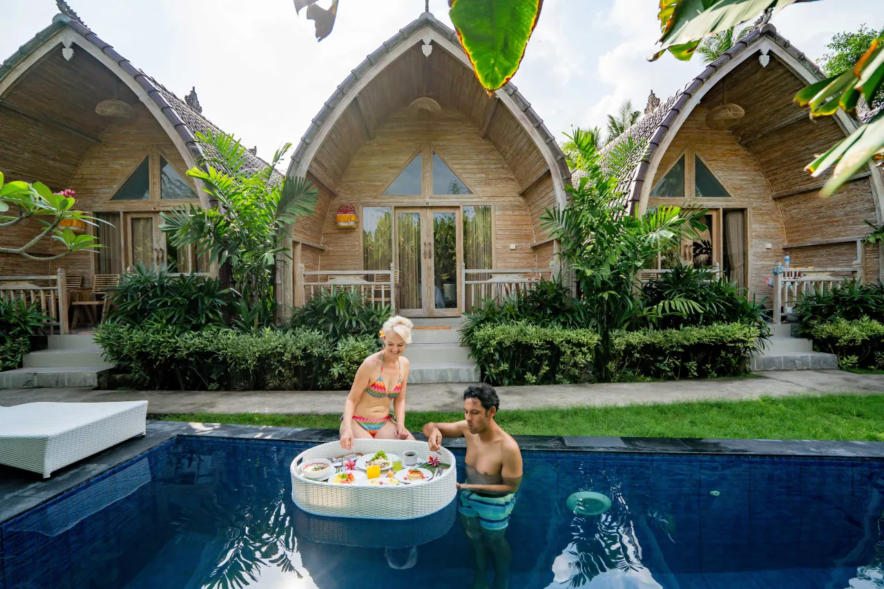 A newlywed couple enjoying a romantic floating breakfast in a private pool during their Bali honeymoon.