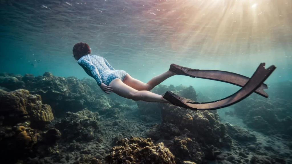 A person snorkeling in clear blue waters with colorful fish in Nusa Penida.