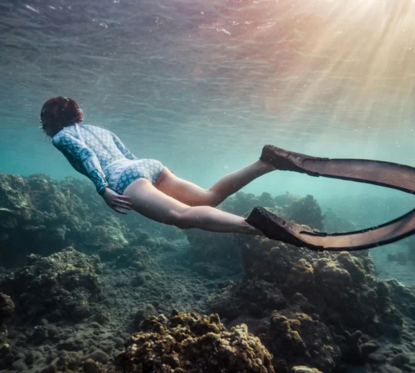 A person snorkeling in clear blue waters with colorful fish in Nusa Penida.