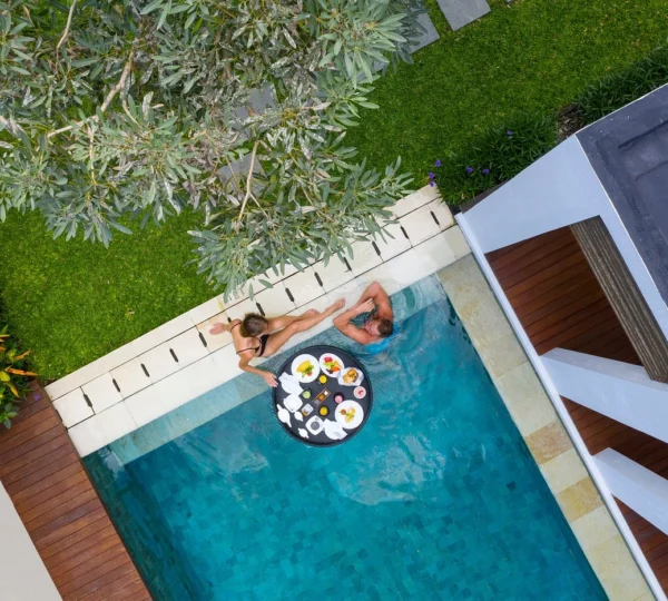 A split image contrasting two distinct romantic vibes in Bali. On one side, a couple enjoys a stunning sunset ocean view from a cliffside in Uluwatu, embodying a luxurious and dramatic honeymoon. On the other side, a couple is surrounded by lush green rice terraces and tropical foliage in Ubud, suggesting a serene, cultural, and nature-immersed romantic experience.