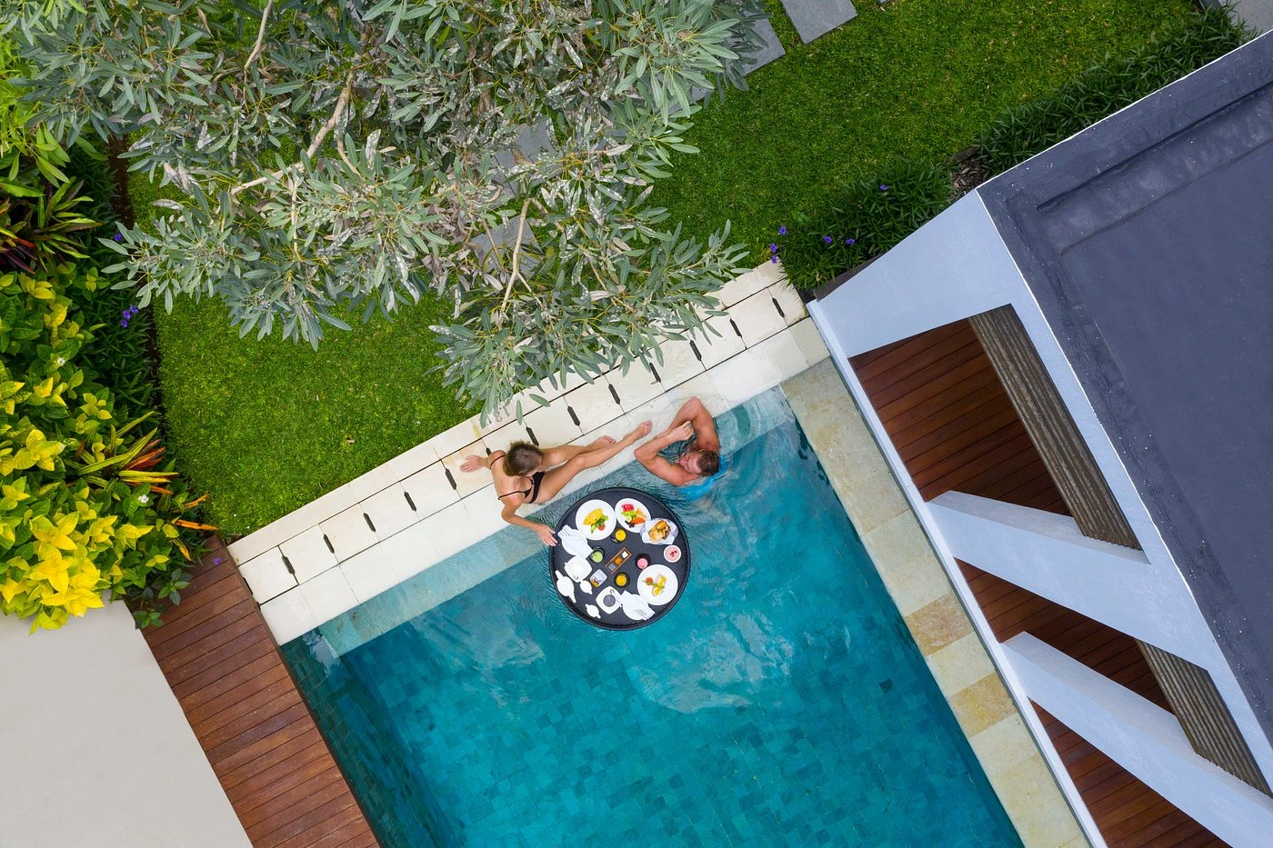 A split image contrasting two distinct romantic vibes in Bali. On one side, a couple enjoys a stunning sunset ocean view from a cliffside in Uluwatu, embodying a luxurious and dramatic honeymoon. On the other side, a couple is surrounded by lush green rice terraces and tropical foliage in Ubud, suggesting a serene, cultural, and nature-immersed romantic experience.