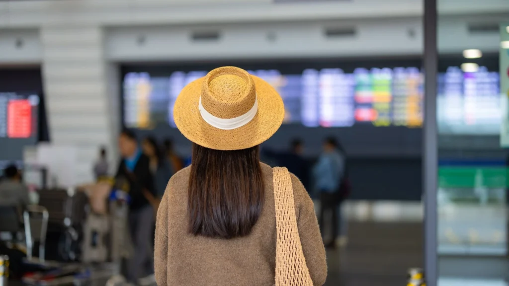 A tourist is calmly and confidently navigating the busy arrival hall of Bali's Ngurah Rai International Airport, following foolproof strategies to avoid common airport scams and find legitimate transportation.