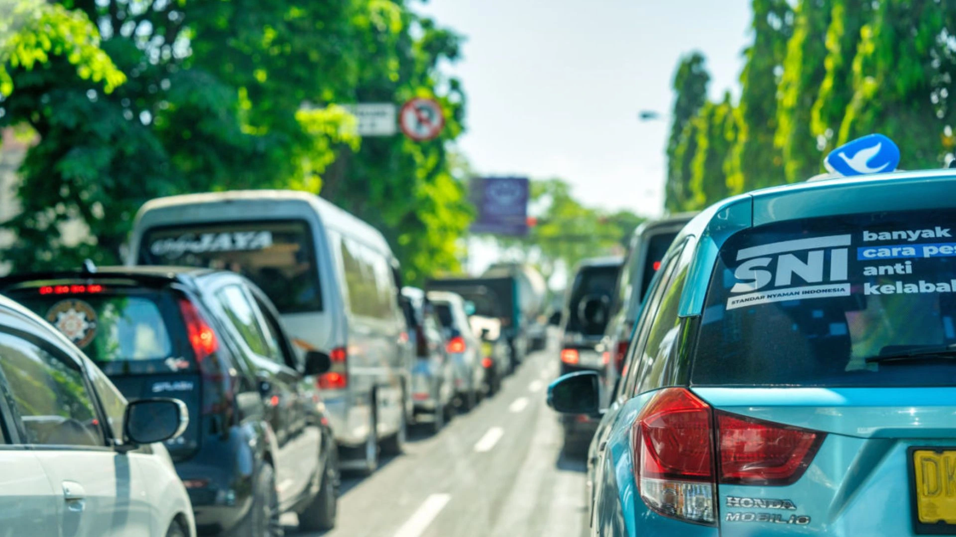 Traffic jam in Bali with a blue taxi called Blue Bird Taxi. The scene shows busy roads during the holiday season.