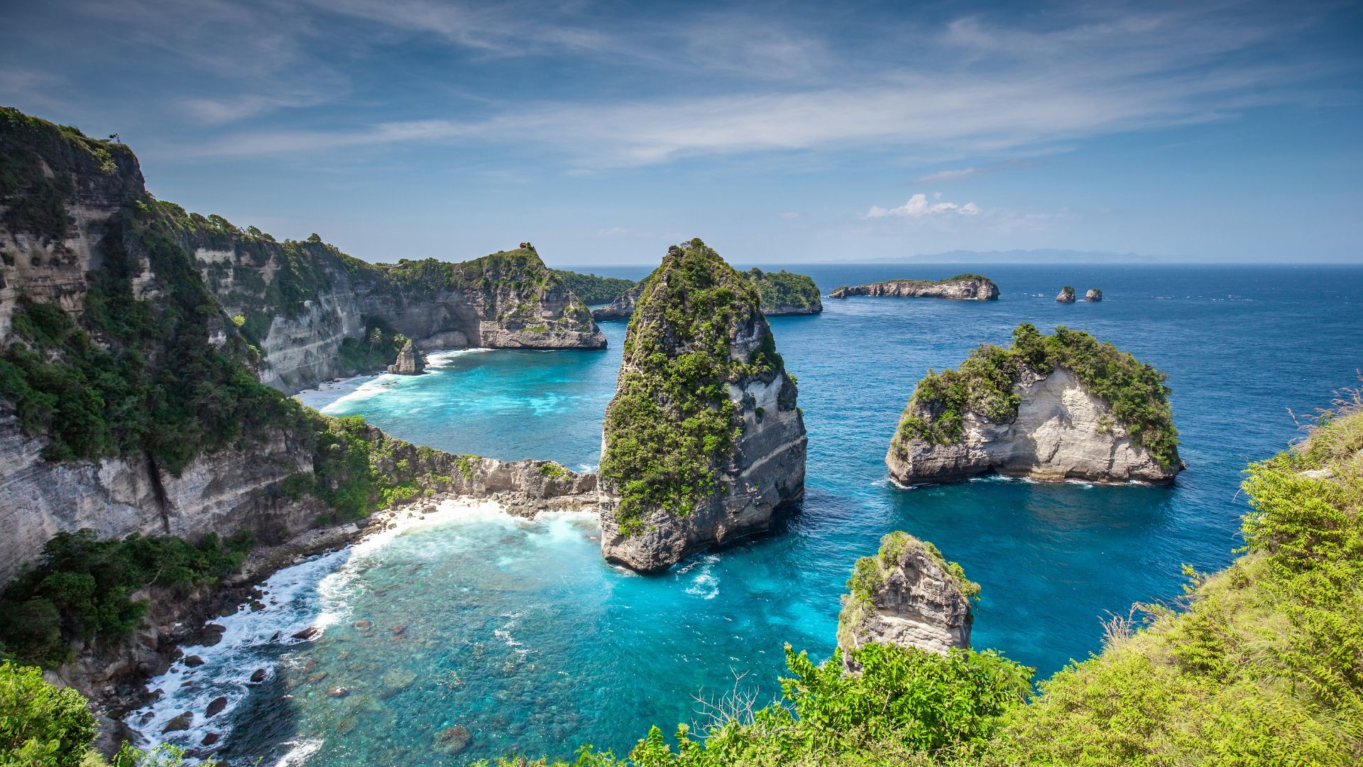 A famous Bali tourist spot shows cliffs and a beautiful natural beach. The scenery looks stunning and unspoiled.