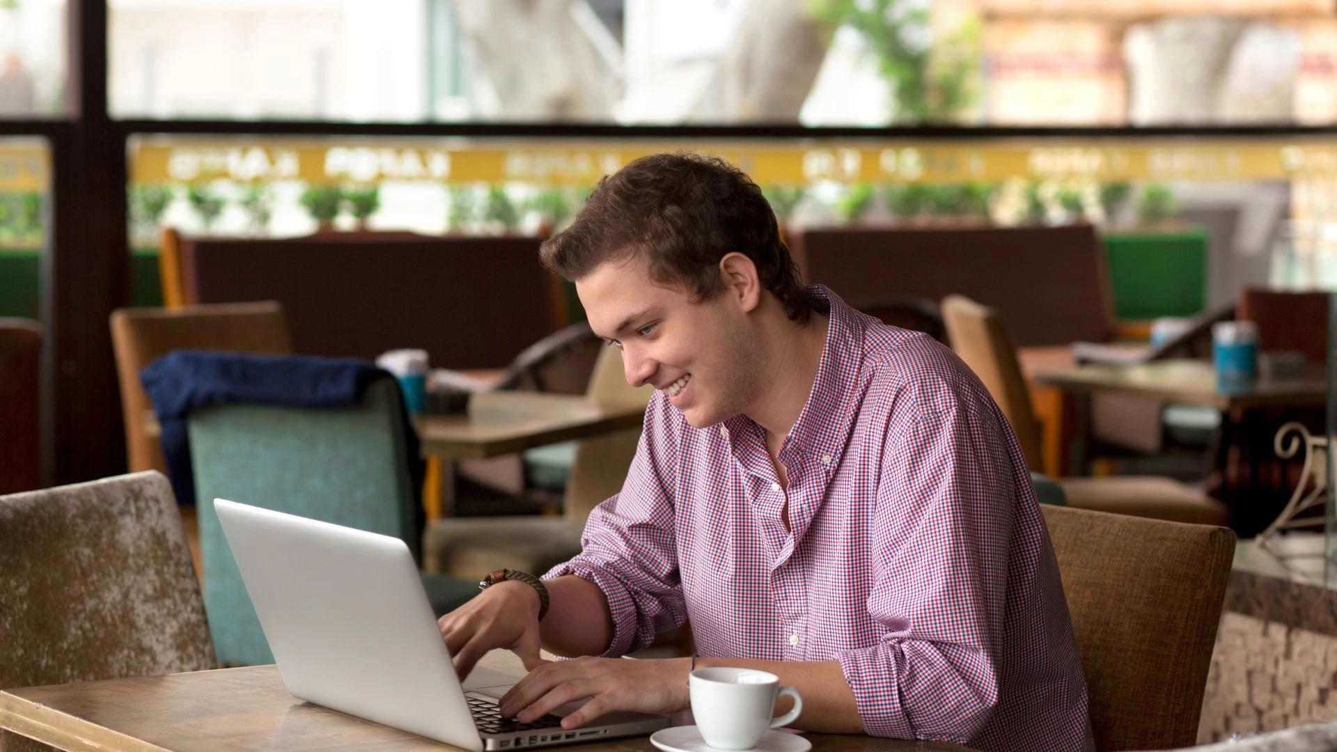 A digital nomad in Bali using their laptop and smartphone to find information, highlighting the necessity of a reliable local SIM card for a stable internet connection.