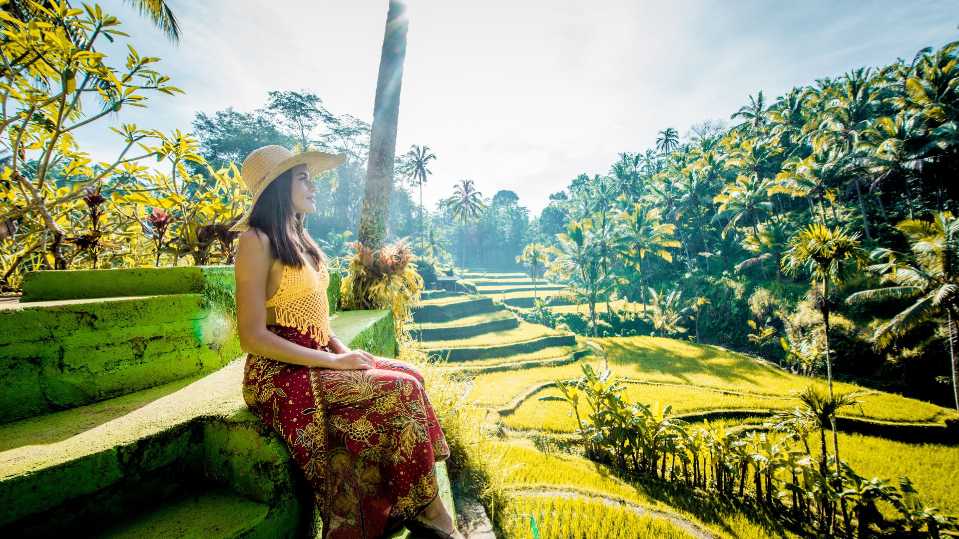 A female tourist poses near rice fields in Ubud. The green landscape looks peaceful and natural.