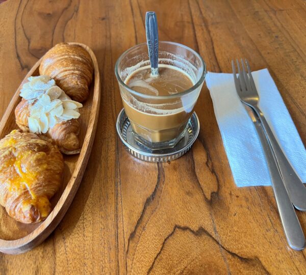 A glass of dark coffee with sweet condensed milk at the bottom, stirred into a strong and sweet brew, served simply without latte art — classic, old-style coffee.