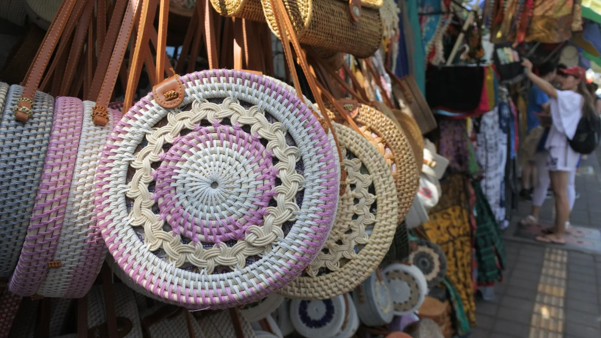Colorful fabrics, handcrafted jewelry, and intricate wood carvings displayed at Ubud Art Market in Bali.