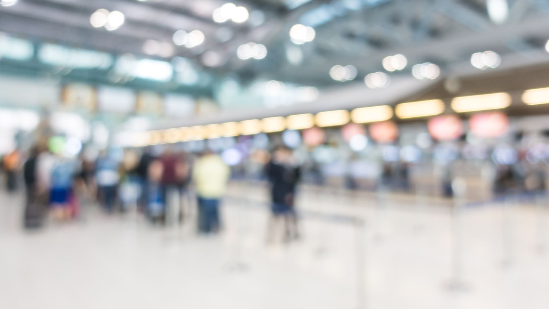 A crowded and chaotic scene at Bali's Ngurah Rai International Airport, with tourists appearing overwhelmed by aggressive taxi drivers and unofficial guides vying for their attention. The image visually represents the reasons why the airport can be a "scammer's paradise" for unsuspecting travelers.