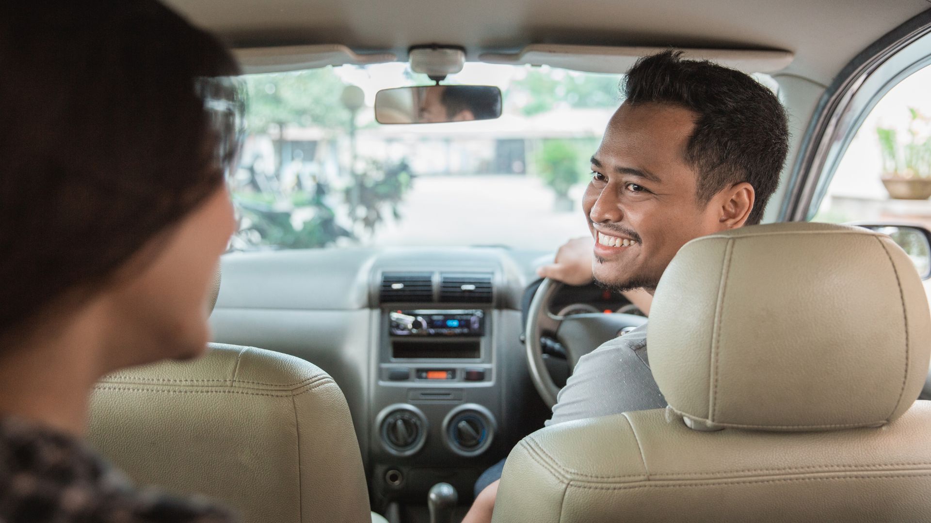 A local Bali driver welcoming tourists at the airport for their vacation. The scene shows warm hospitality and friendly service.