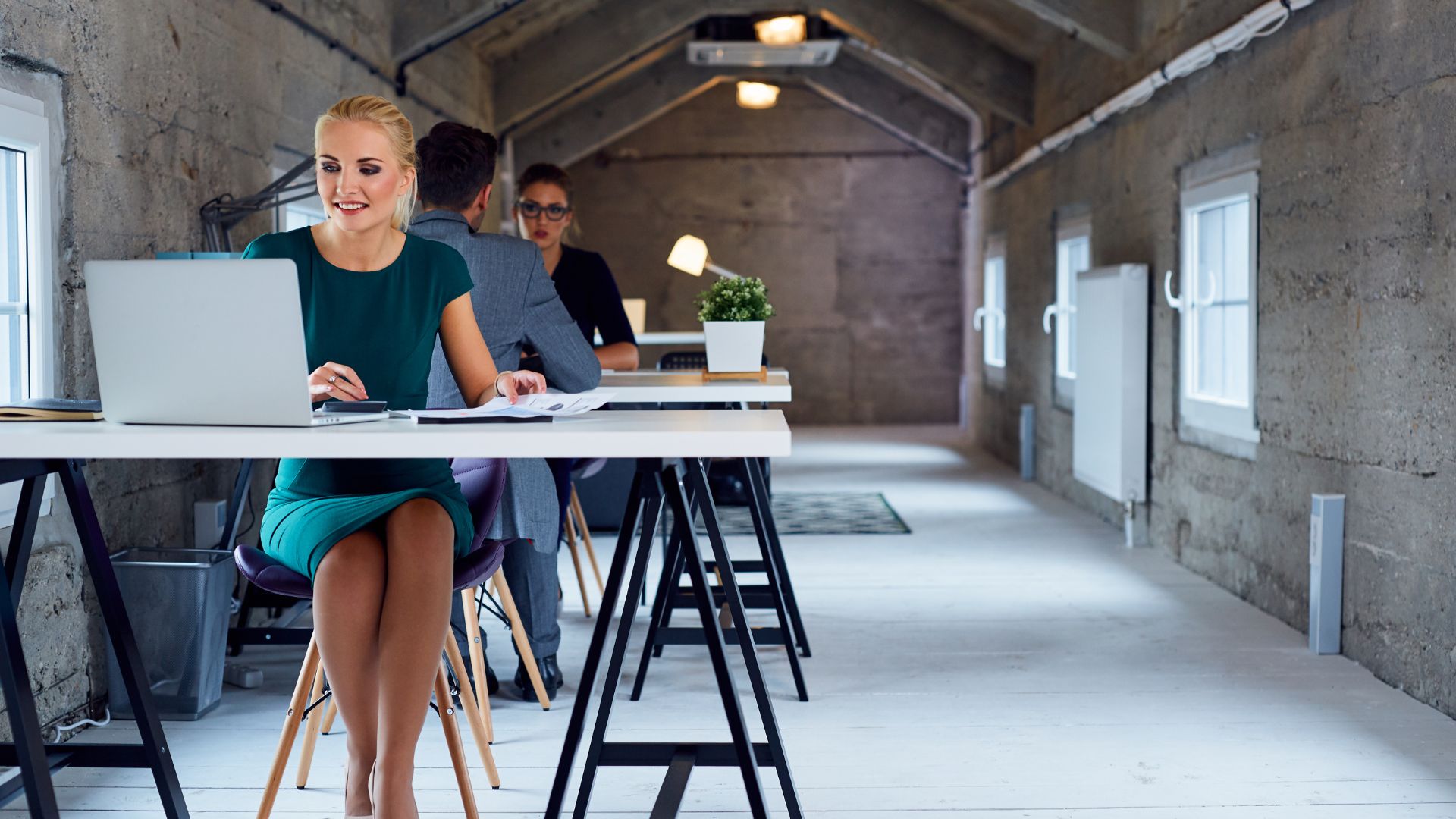 Several digital nomads work in a Bali coworking space with unique interior design. Creative decor, open desks, and plants make the room feel lively.