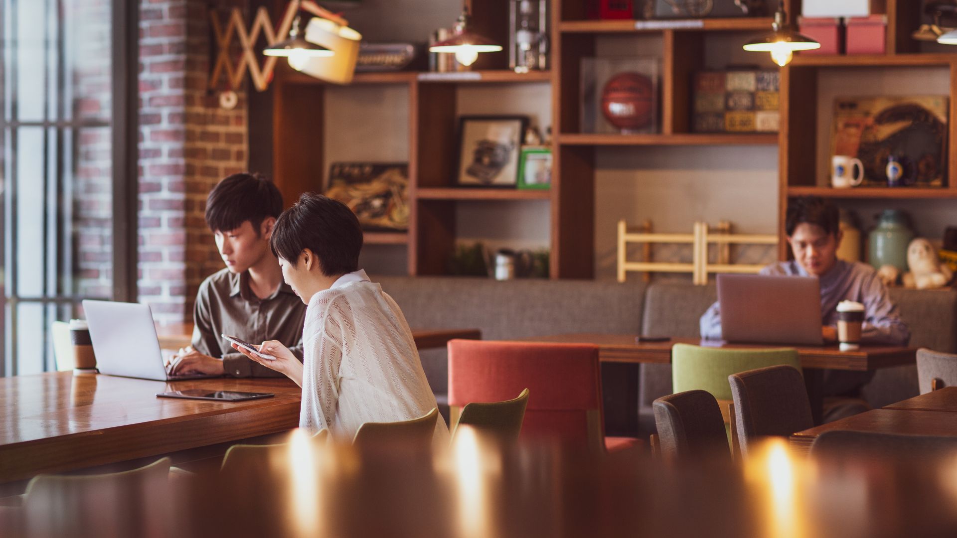 Interior of a Bali café with several digital nomads working on laptops. Warm lighting, wooden tables, and tropical details create a cozy vibe.