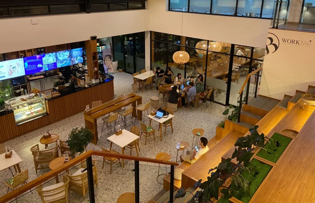 A scenic view inside BWork café that also functions as a coworking space in Canggu, Bali. Large windows, green plants, and quiet seating invite focused work.
