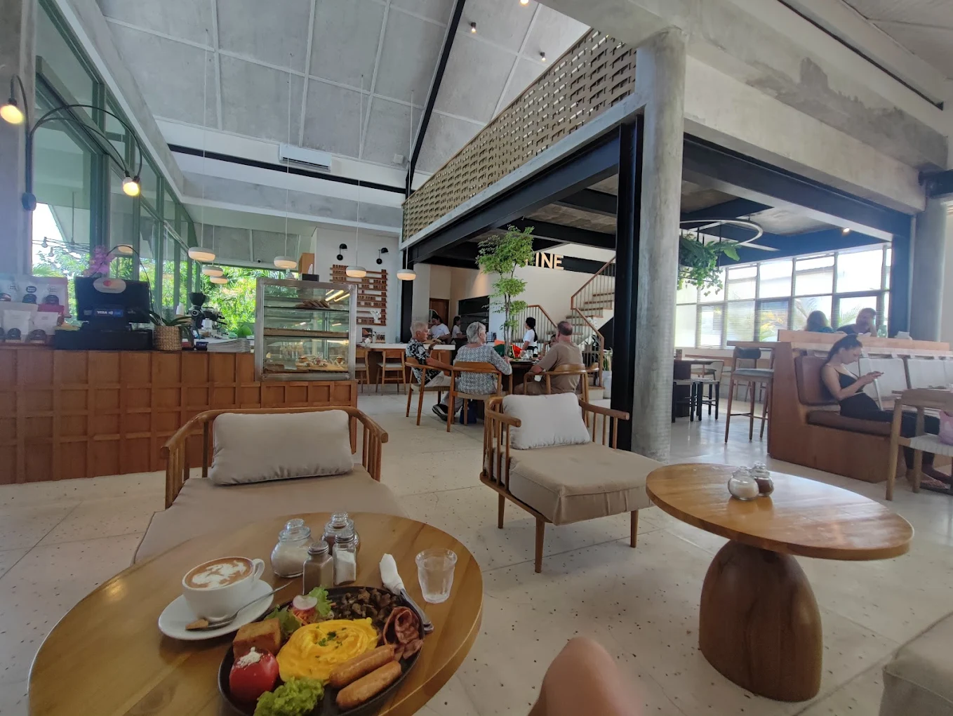 A scenic view inside FINE by Satu Satu café that also functions as a coworking space in Canggu, Bali. Large windows, green plants, and quiet seating invite focused work.