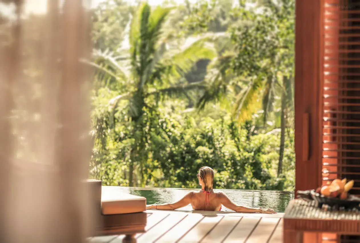 A female tourist swimming in a private pool at the Four Seasons Resort in Sayan, Ubud. She enjoys her leisure time in a luxury villa.