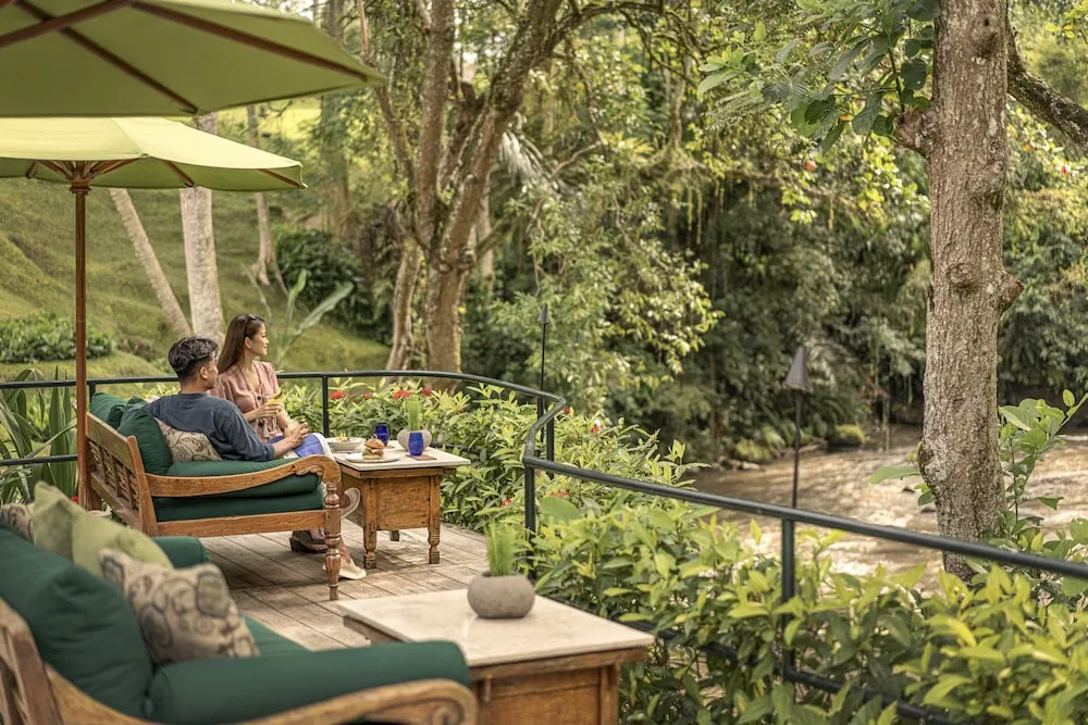 A couple enjoying lunch by the river view at Four Seasons Resort in Sayan, Ubud. The moment combines fine dining with a peaceful setting.