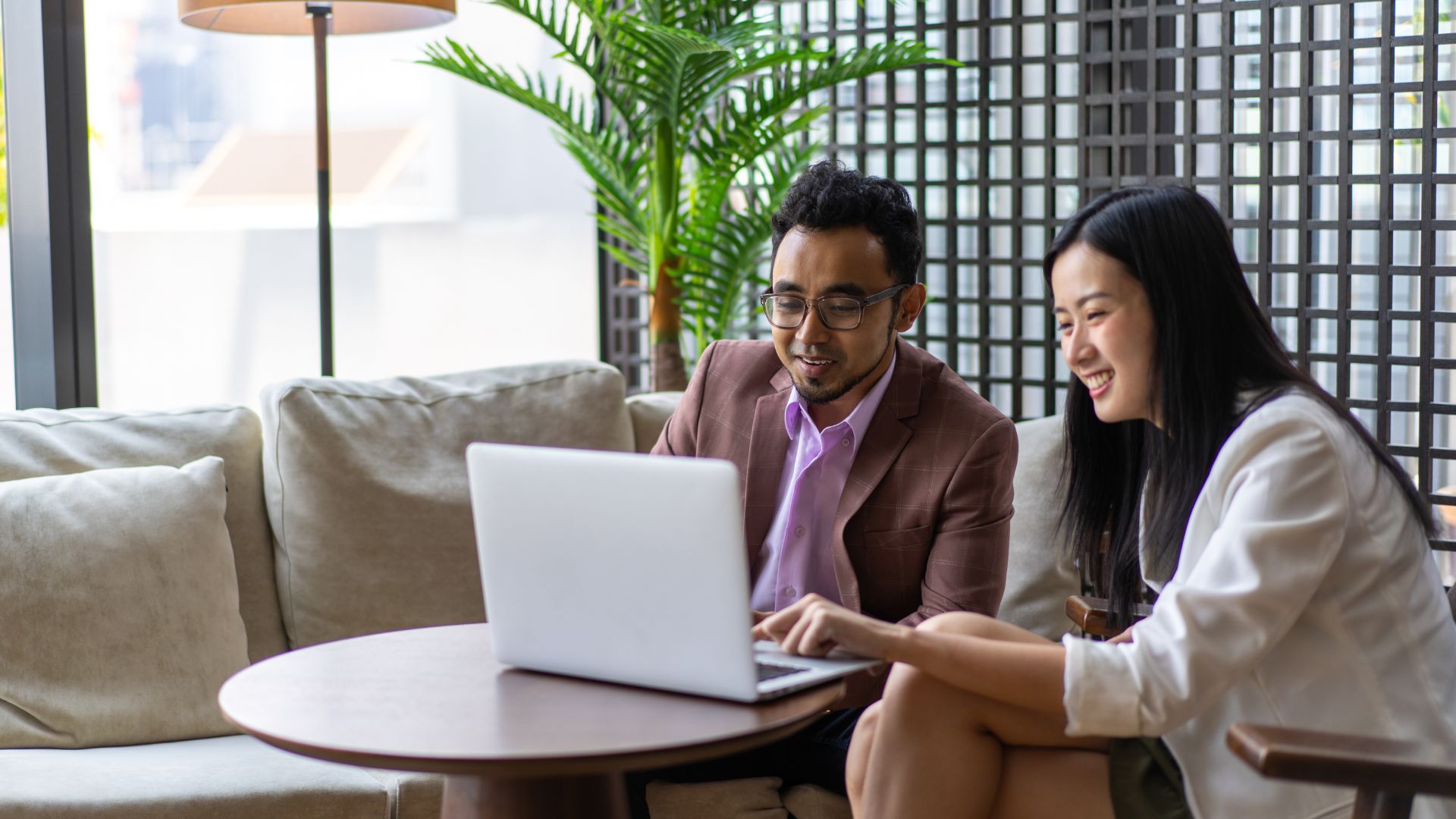 A Bali business owner meets a foreign woman client at a restaurant. They review documents over coffee in a relaxed setting.